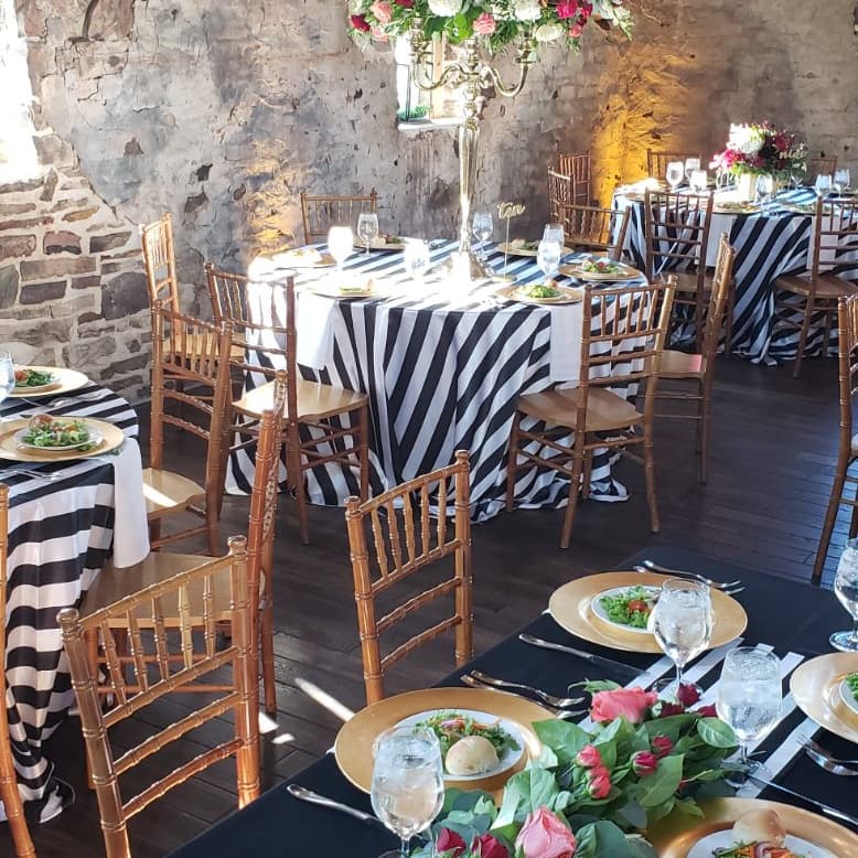 Tall floral arrangement on a striped table against a stone wall