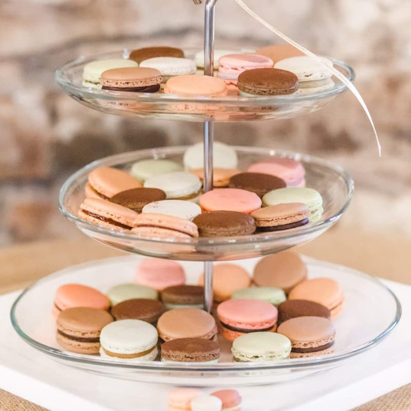 Three-tiered glass stand of pastel macarons tied with a ribbon