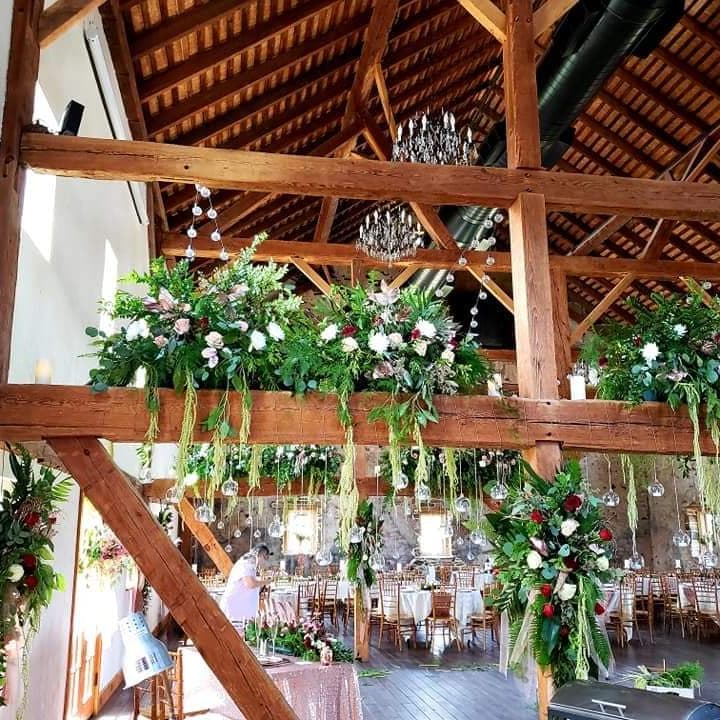 Barn rafters dressed with greenery garlands and crystal chandeliers